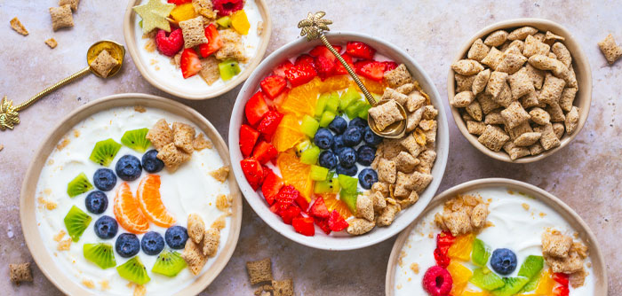 Uppdukad frukost, bowls med havrefras och frukter i regnbågsfärger.